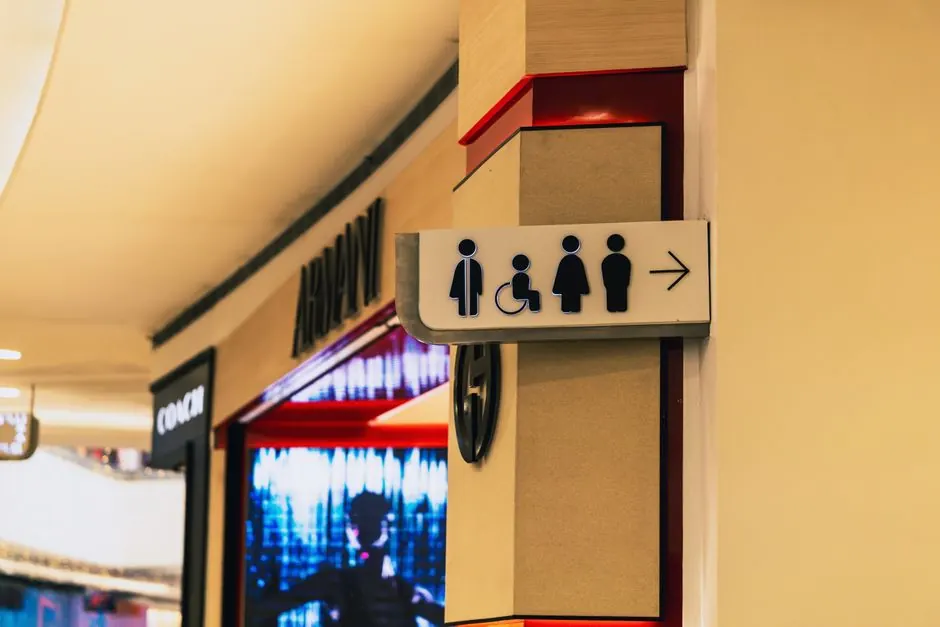 A restroom sign inside a shopping mall guiding to men's, women's, and accessible bathrooms.