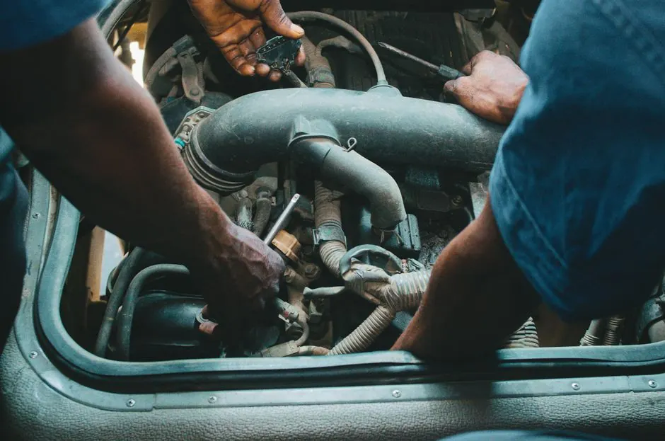 Auto mechanics repairing an engine in a Nigerian workshop. Close-up hands and tools.
